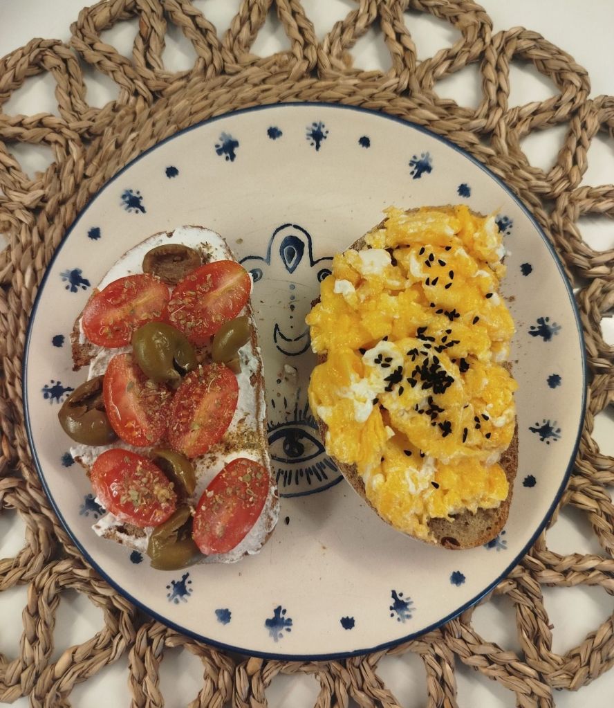 Ekşi mayalı ekmek üzerine çırpılmış yumurta  ve çörek otu ile domatesli, zeytinli, labneli, kahvaltı tabağını sunumu, 